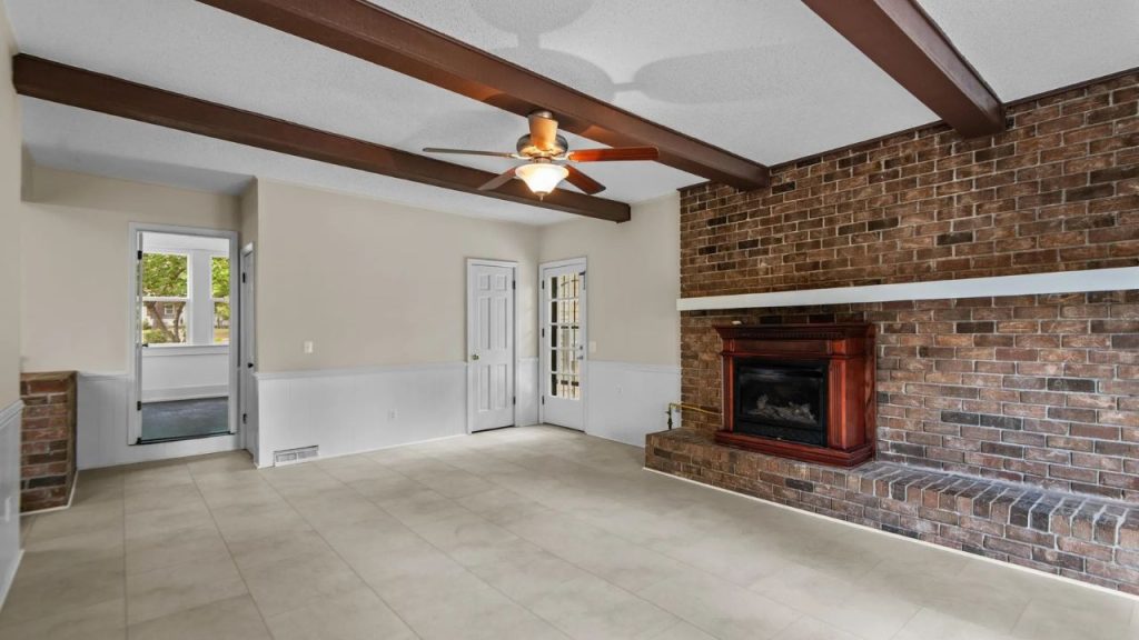 Brick-walled family room with beams and fireplace.