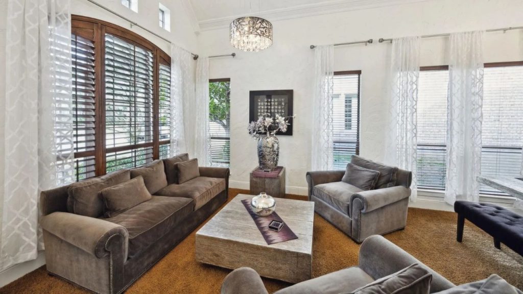 Bright and cozy lounge with soft seating, rustic coffee table, and natural light streaming through sheer curtains.