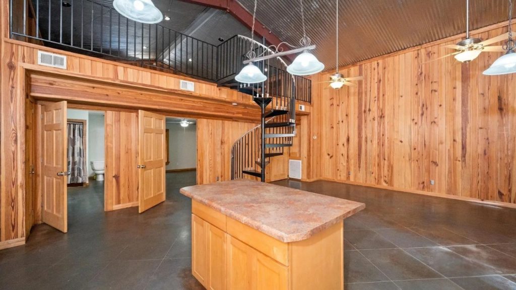 Wood-paneled room with spiral staircase and kitchen island.