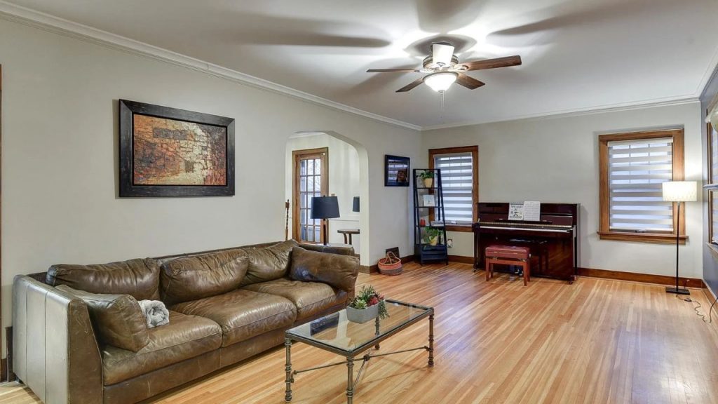 Living room with leather couch, upright piano, and hardwood floors.