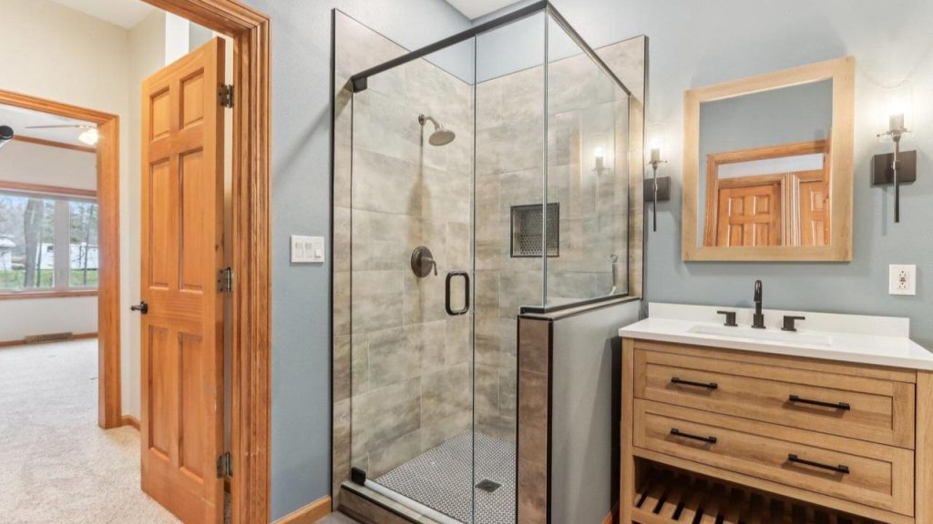 Glass shower with wood vanity and matte black fixtures.