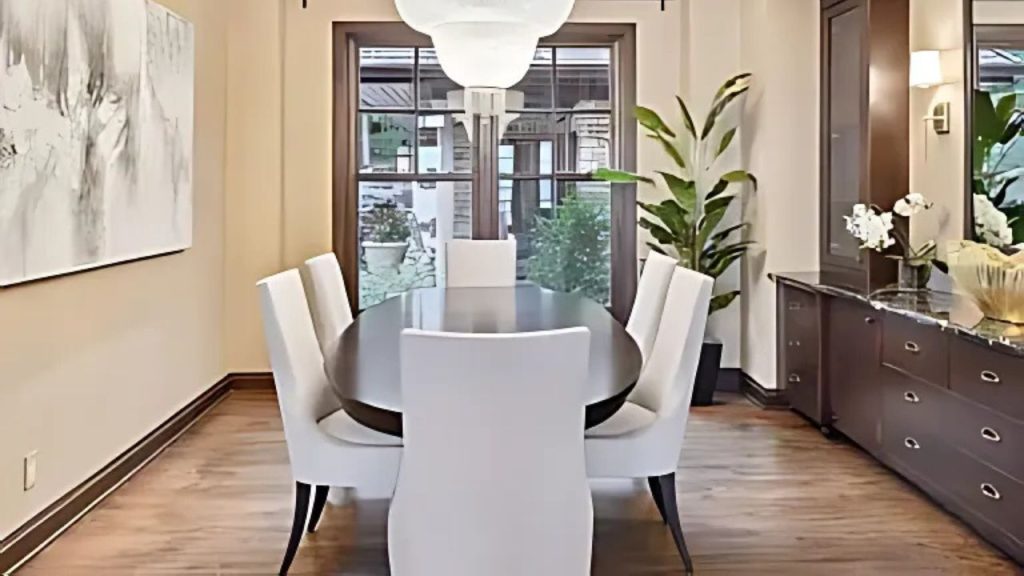 A stylish dining room with a dark wood table, white chairs, and a large window view.