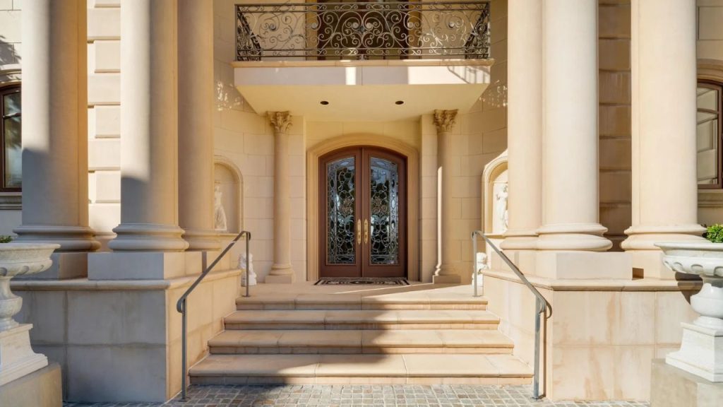 A grand entrance with stone columns, stained glass doors, and a wrought-iron balcony.