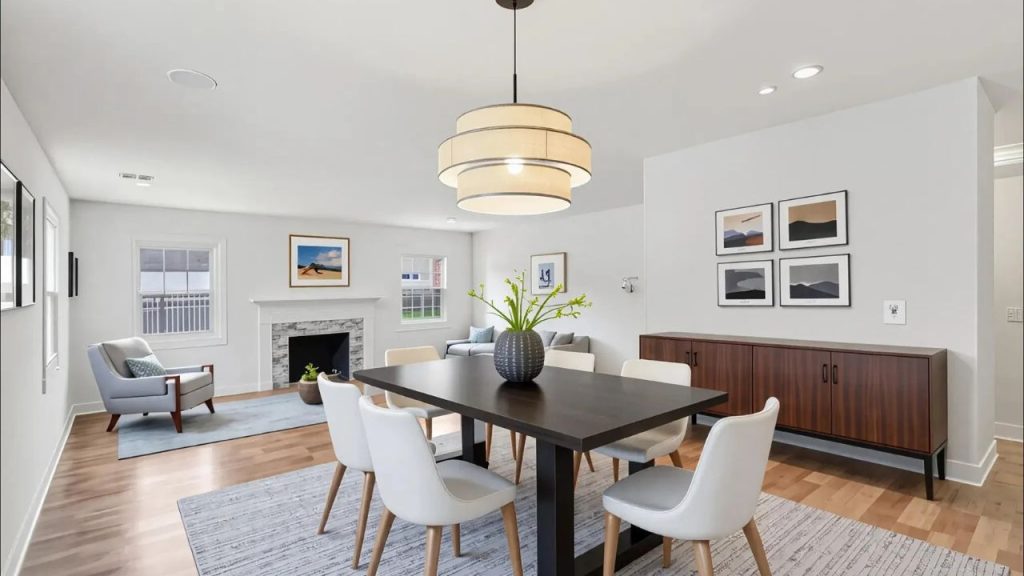 A stylish dining area with a wooden table, white chairs, and a pendant light, featuring a fireplace and large windows.