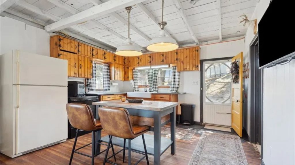 Rustic kitchen with wooden cabinets, a farmhouse sink, and a cozy island with leather barstools.