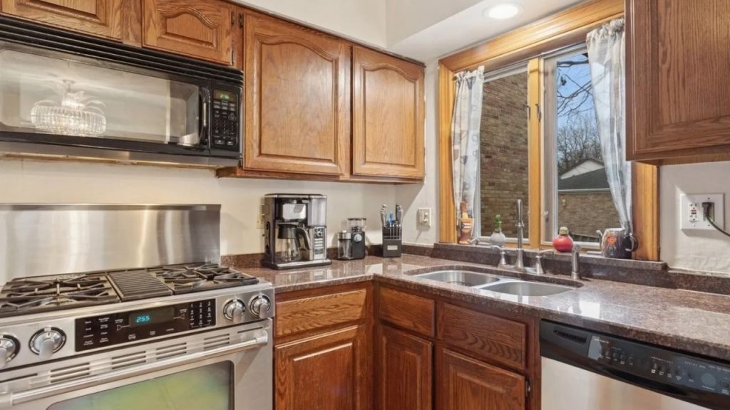 Cozy corner kitchen with wood cabinets, double sink, and stainless appliances.