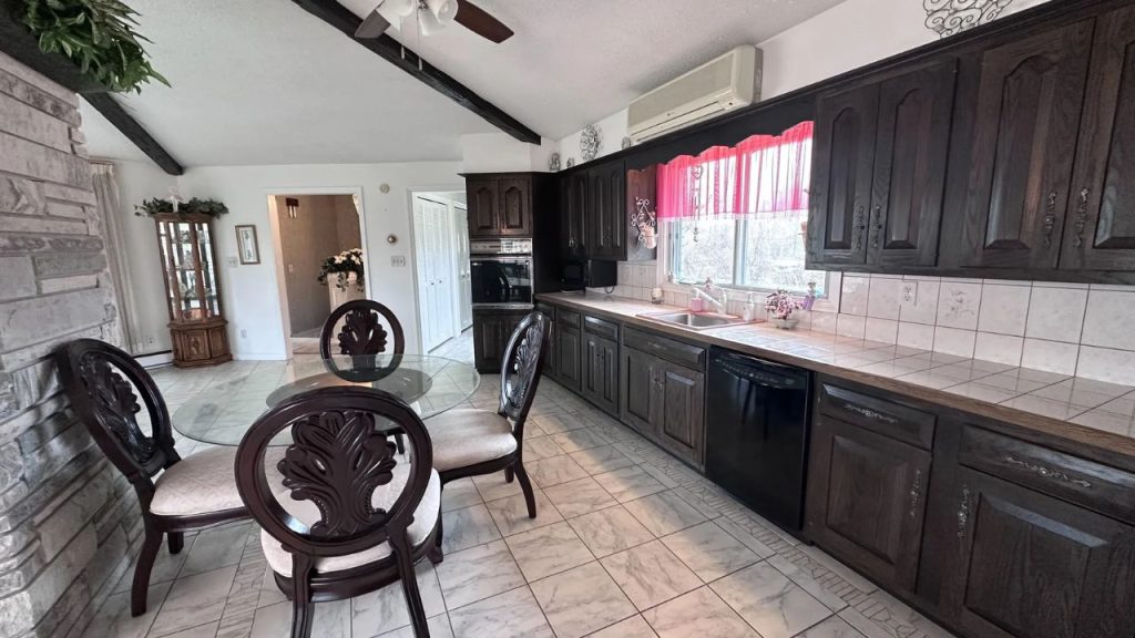 Bright kitchen with dark cabinets, stone wall, and a small dining table.
