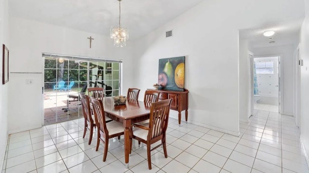 A dining room with a wooden table, chandelier, and patio view through glass doors.
