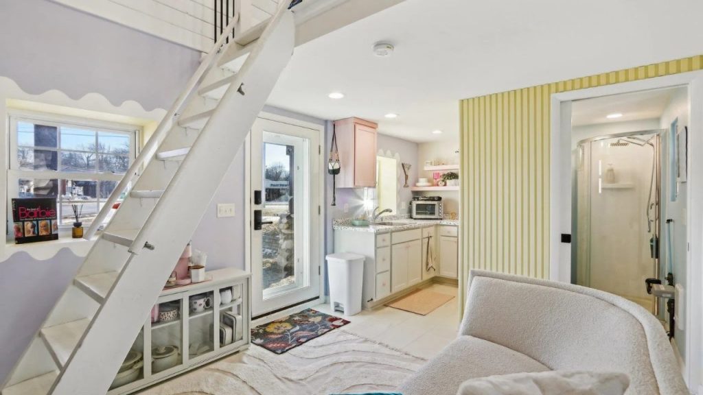 Bright cottage kitchen with pastel colors, loft ladder, and curved glass shower.