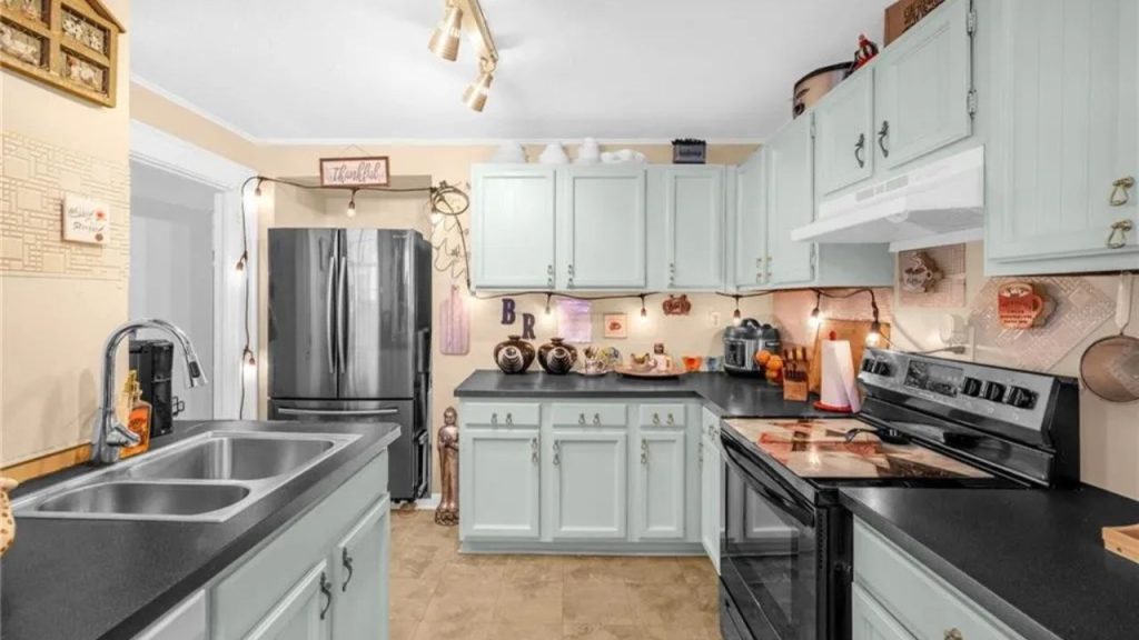 Light mint kitchen with black counters, string lights, and warm decor touches.