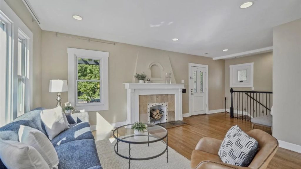 Living room with fireplace, wood floors, and stairway.