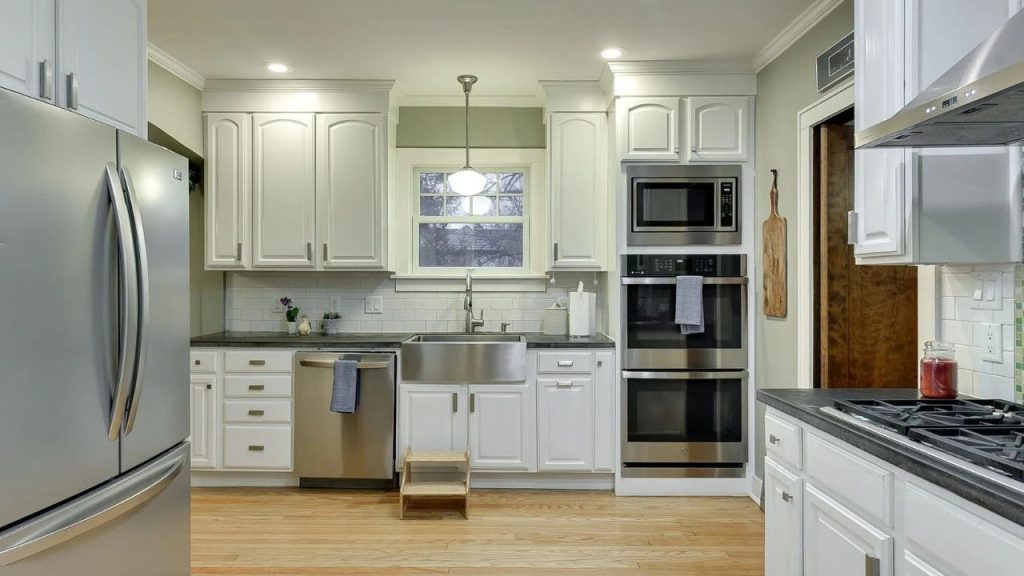 White kitchen with farmhouse sink and built-in stainless appliances.