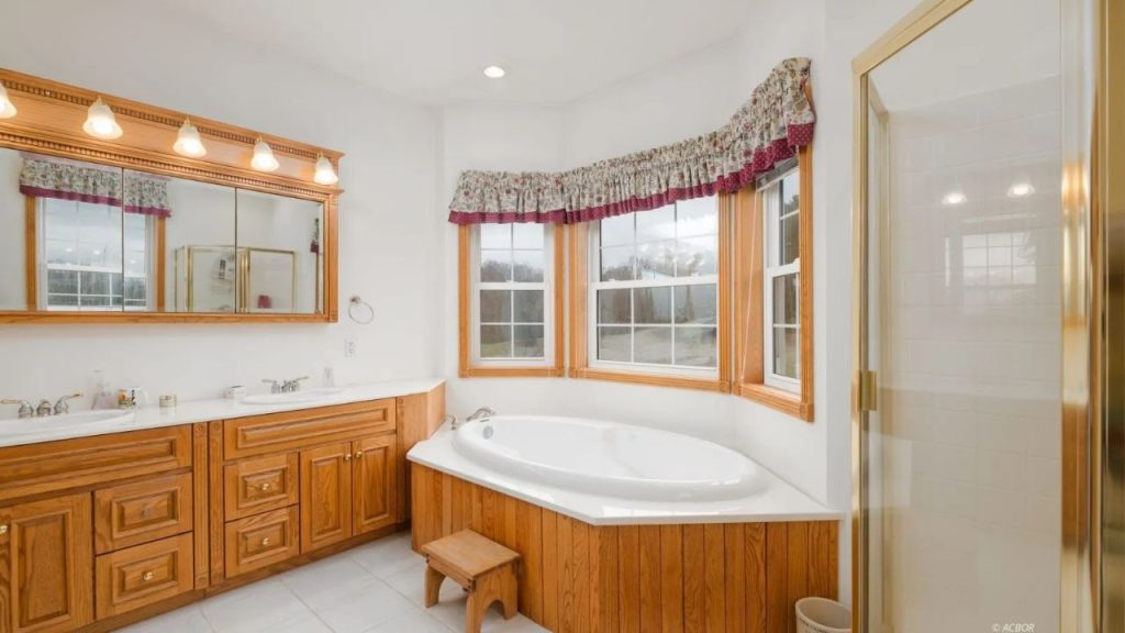 Bright bathroom with a built-in soaking tub, double vanity, and glass shower.