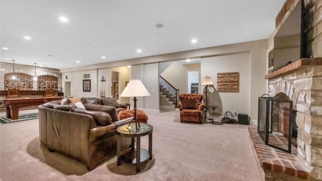 Cozy basement with a fireplace, leather seating, and a pool table.