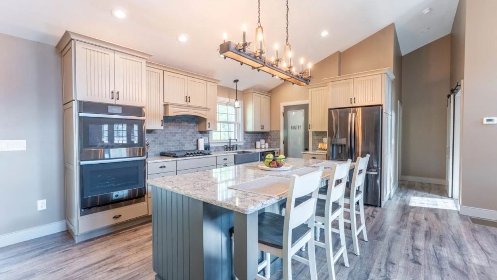 Farmhouse kitchen with beadboard cabinets, granite island, and rustic chandelier.