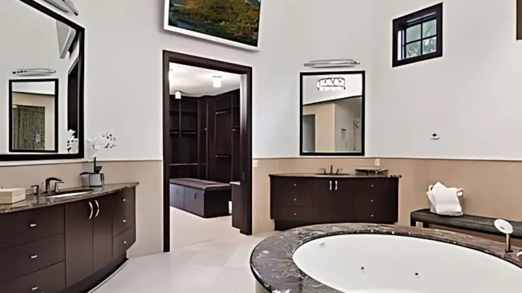 A luxurious bathroom with a soaking tub, dual vanities, and a walk-in closet view.