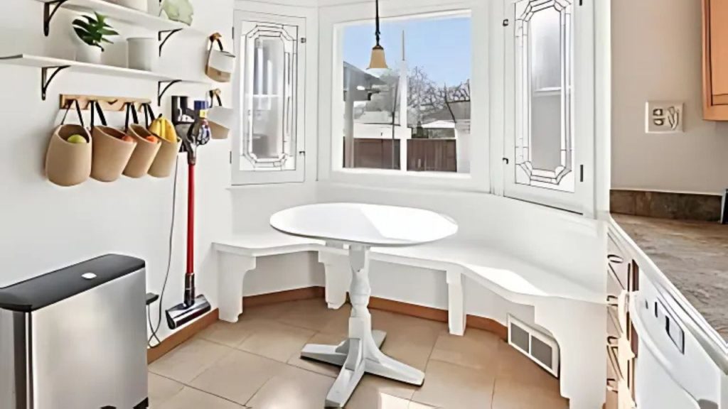 A sunny kitchen nook with a round table, built-in bench, and decorative windows.