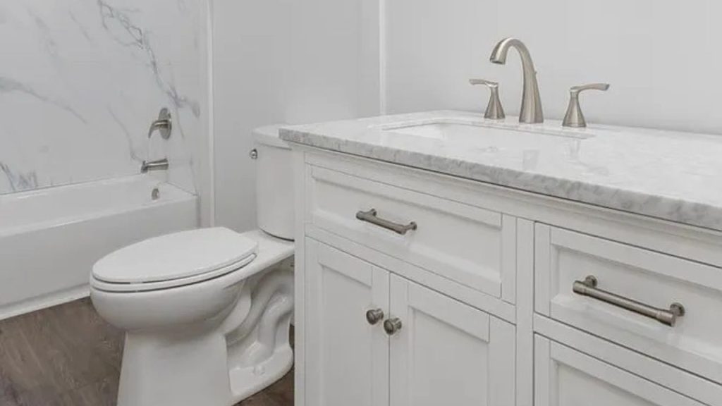 A serene bathroom with a marble vanity, double sinks, bathtub, and hardwood floors.