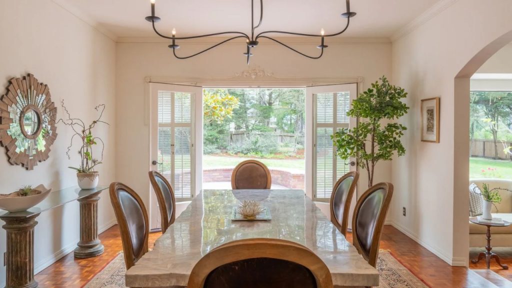 A sunlit dining space with a double-sided fireplace and large windows.