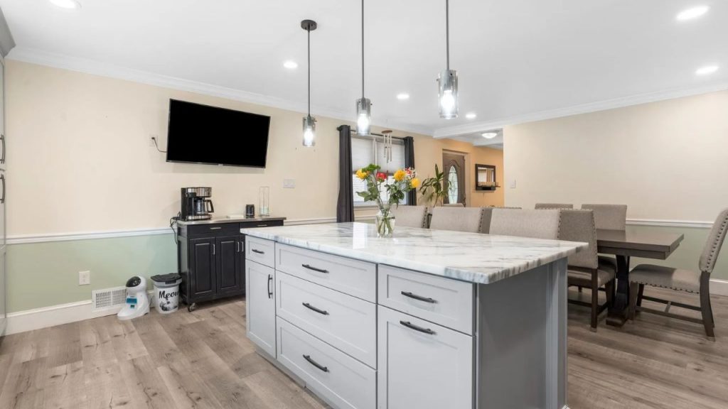 Marble kitchen island with pendant lights, coffee station, and view to front entry.