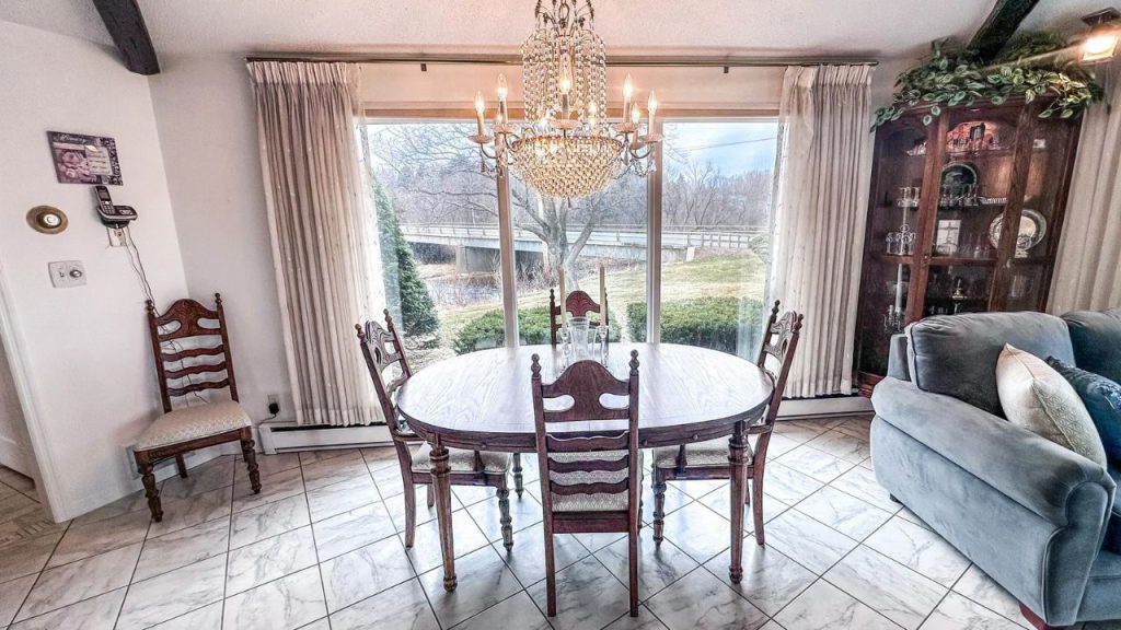 Bright dining room with wood table, crystal chandelier, and large windows.