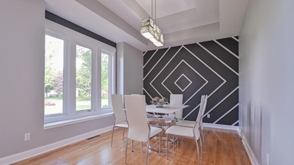 Modern dining room with geometric accent wall and large windows.