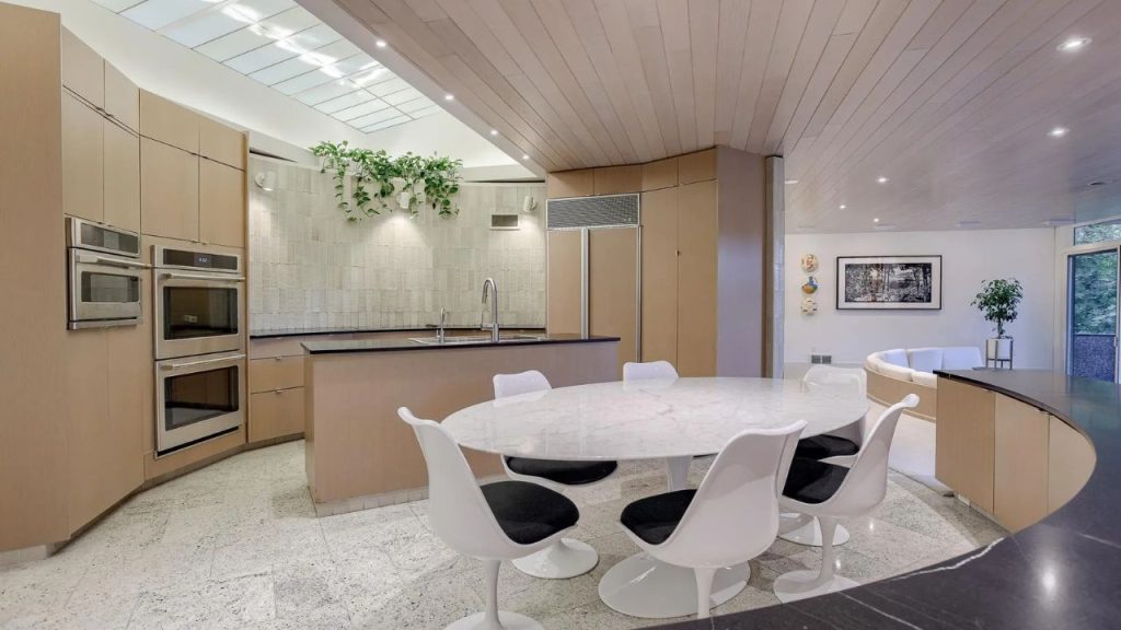 Curved wood kitchen with mid-century dining set and skylight.