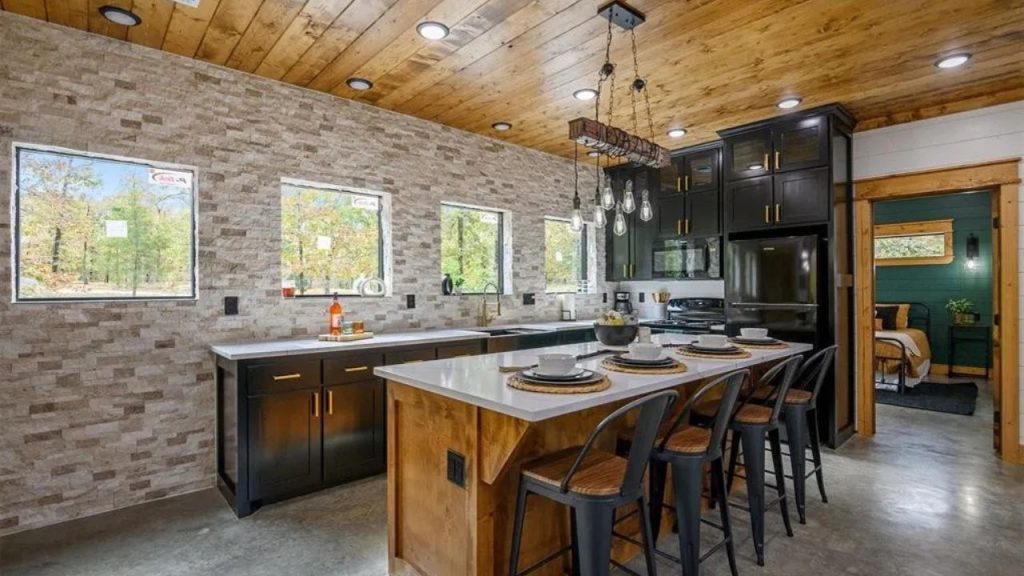Bright kitchen with black cabinets, wood ceiling, and large island