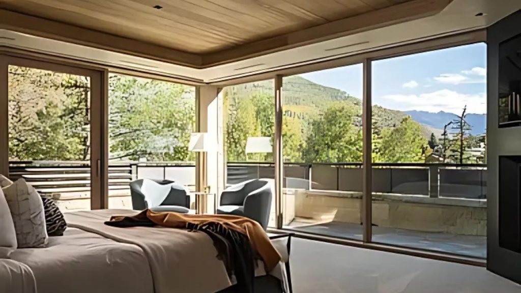 A cozy bedroom with a plush bed and large windows overlooking mountains.