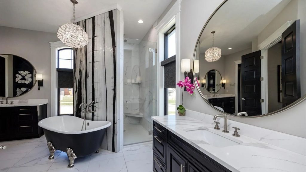 A luxurious bathroom with a black clawfoot tub, glass shower, marble countertops, and crystal chandeliers, exuding elegance and calm.