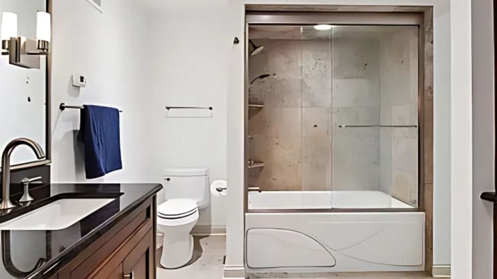 A minimalist bathroom with a dark vanity, glass shower, and white tub.
