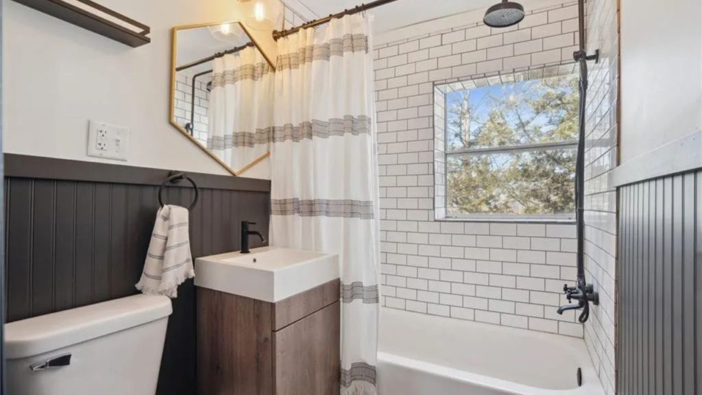 Bright bathroom with subway tiles, a rustic vanity, and a gold-framed mirror.