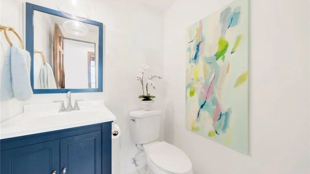 Small powder room with blue vanity and abstract wall art.