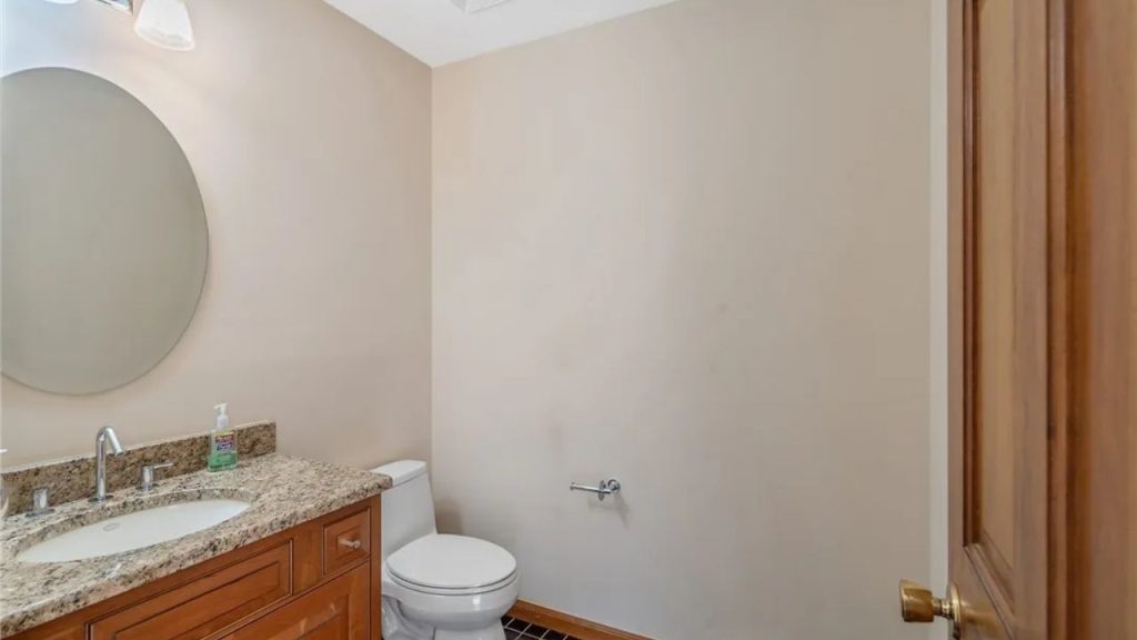 Small powder room with wood vanity and granite countertop.