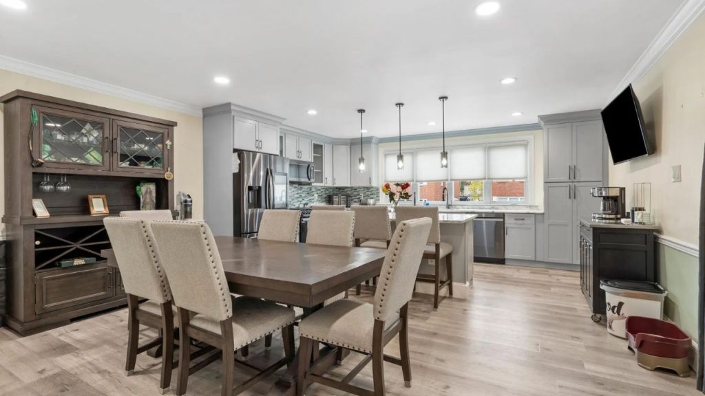 Open kitchen with gray cabinets, marble island, and adjacent dining area.