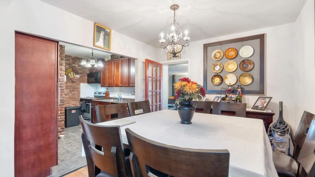 Dining room opening into a cozy kitchen with wood cabinets and brick accents.