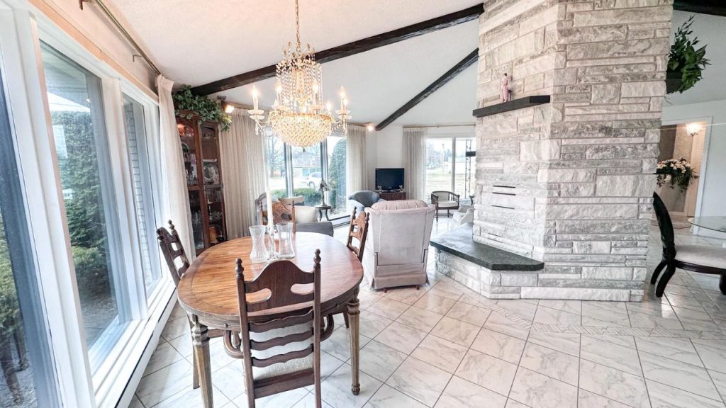 Bright open living and dining room with stone fireplace and wood beams.