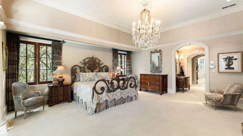 Elegant bedroom with ornate bed, chandelier, and antique furnishings.