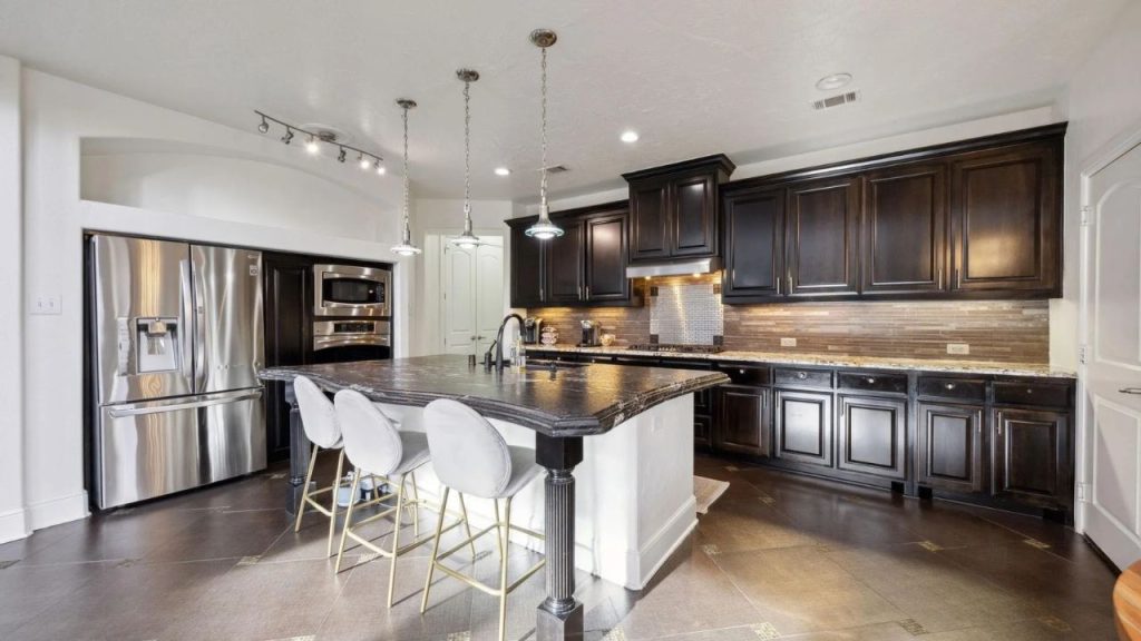Large kitchen with dark cabinets, center island, and stainless steel appliances.