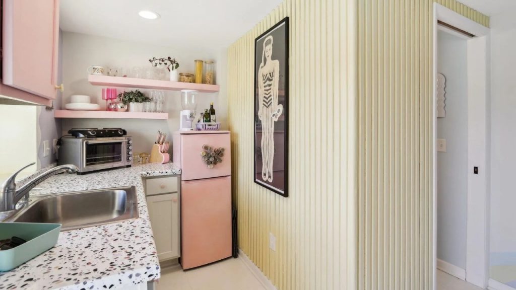 Retro-style kitchen with pastel pink fridge and terrazzo countertops.