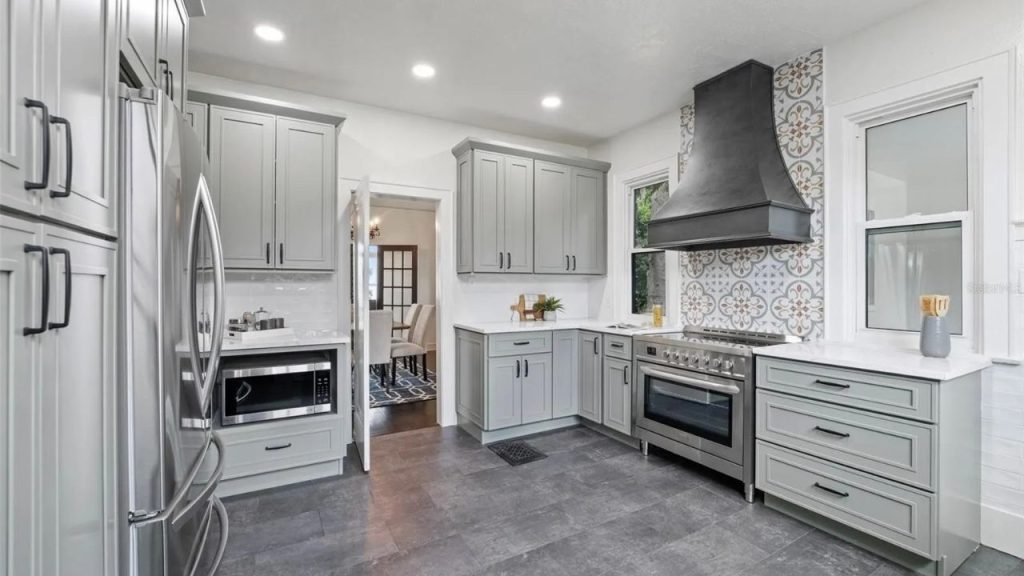 Gray kitchen with patterned tile and black range hood.