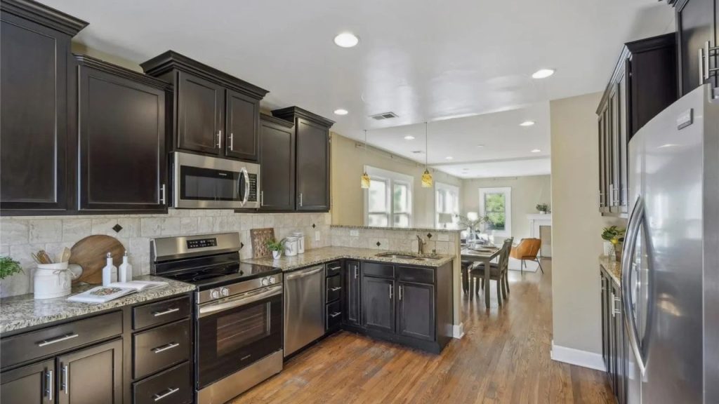 Open kitchen with dark cabinets leading to a dining and living area.