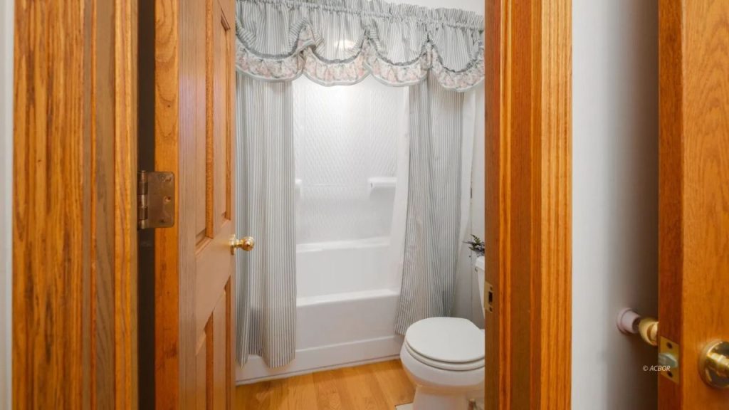 Traditional bathroom with blue-striped curtains, wooden doors, and a cozy ambiance.