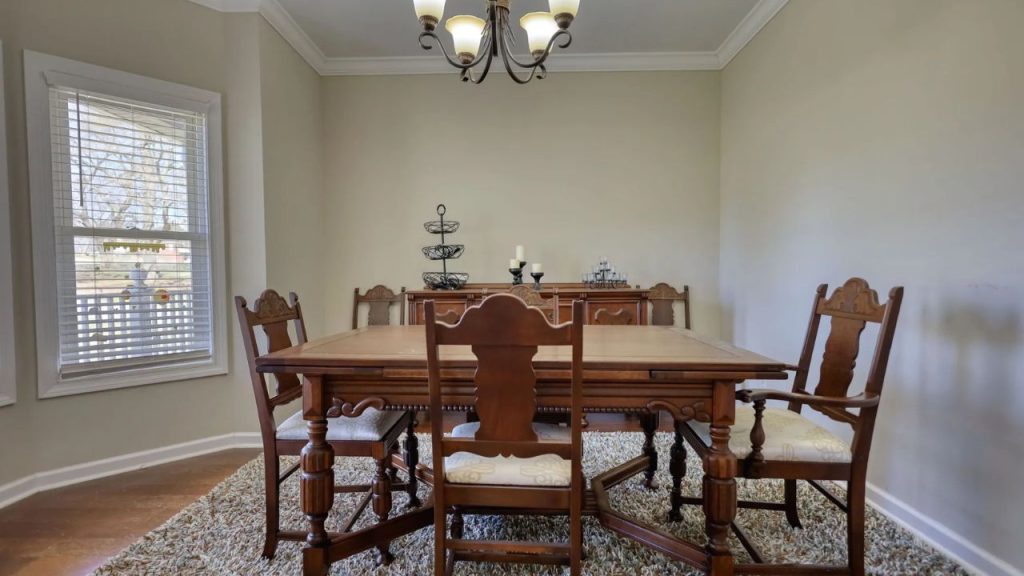 Classic dining room with carved wooden table, tall chairs, and soft natural light.