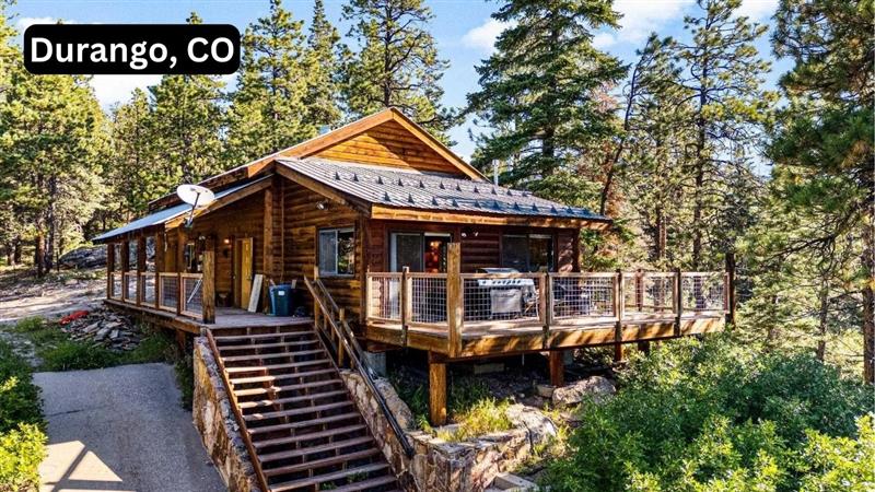 Rustic 2-bedroom cabin in Durango, CO surrounded by pine trees, featuring a large deck and wooden exterior.