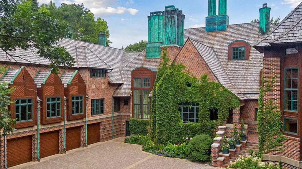 A luxurious brick home with ivy, copper chimneys, and a landscaped courtyard on a large lot in Wayzata, MN.