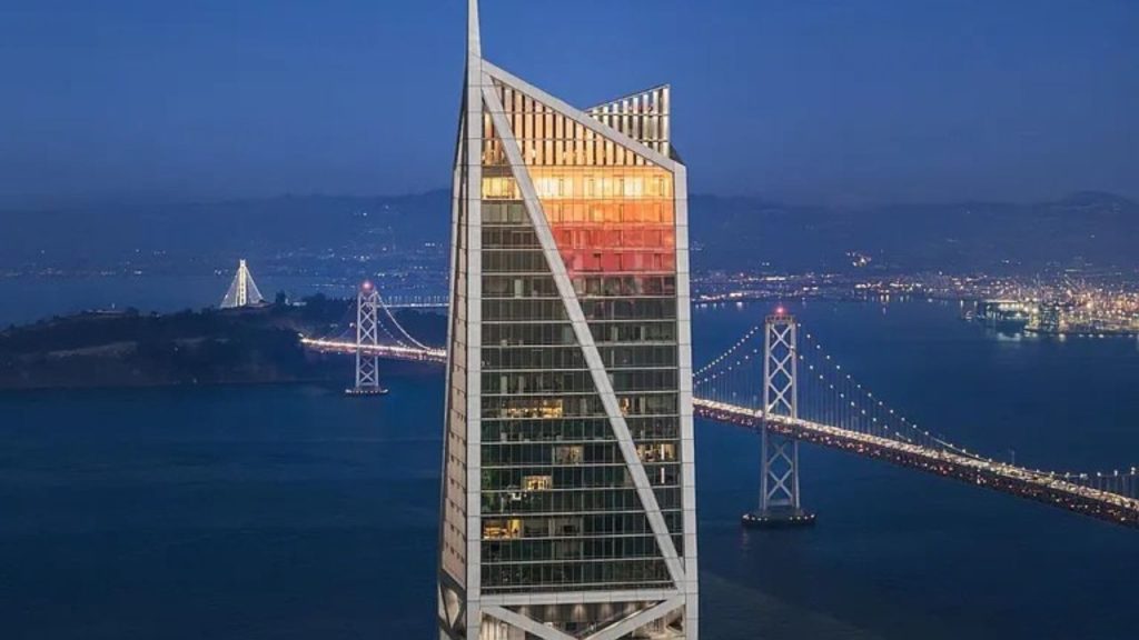 A modern condominium with a striking design, overlooking the illuminated Golden Gate Bridge at dusk.