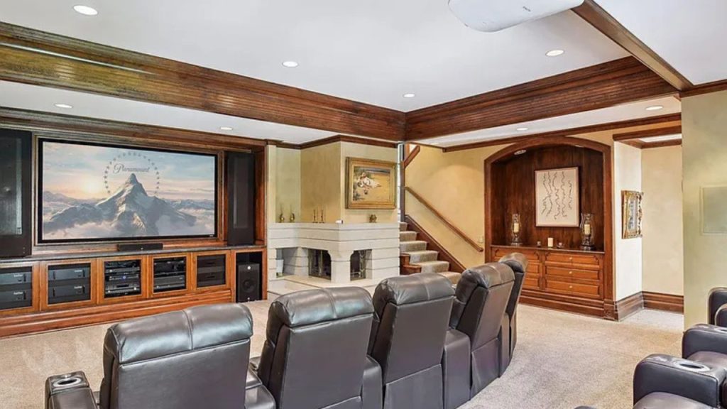 A cozy home theater with leather recliners, a large screen, and a fireplace.