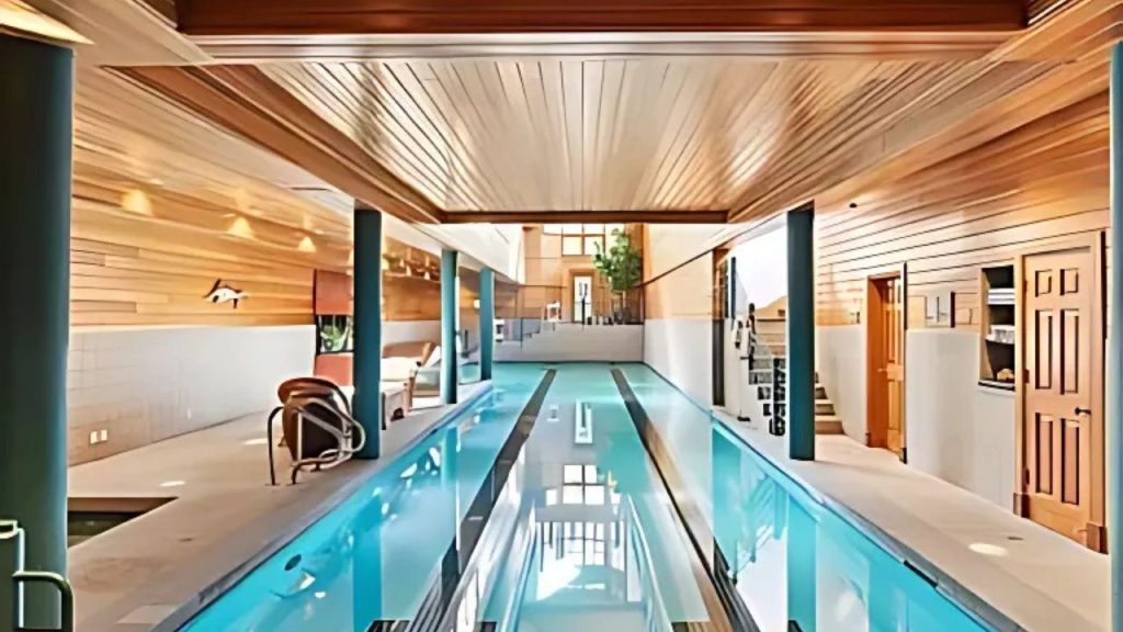 A bright indoor pool with wooden ceilings, teal pillars, and cozy seating.