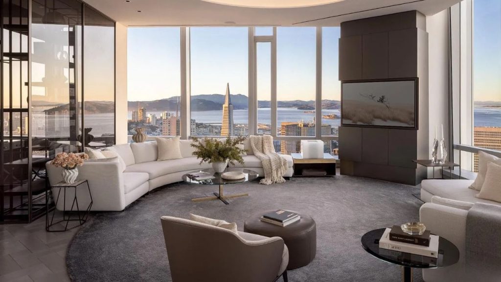 A bright living area with large windows showcasing San Francisco Bay, featuring a white sofa, modern decor, and a large TV.